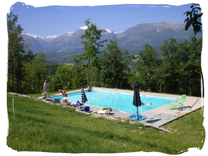 The pool in early June with Amandola and a backdrop of the snow-capped Sibillini Mountains